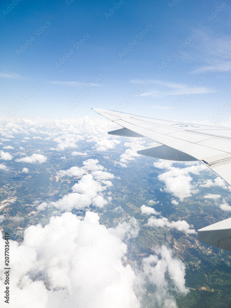 Fototapeta premium View from an airplane window looking out over beautiful clouds and blue sky during flight.