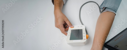 Canvastavla Person using a digital blood pressure monitor at home to check blood pressure, representing hypertension screening, cardiovascular health, preventive healthcare, medical monitoring, and wellness