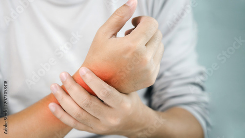 Close-up of a person holding a painful wrist with highlighted inflammation, illustrating wrist pain, repetitive strain injury, carpal tunnel syndrome, tendonitis, medical care, recovery.