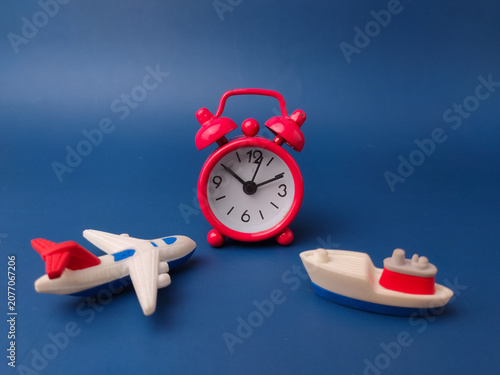 Photos red vintage alarm clock stands between a small toy airplane and a miniature carg