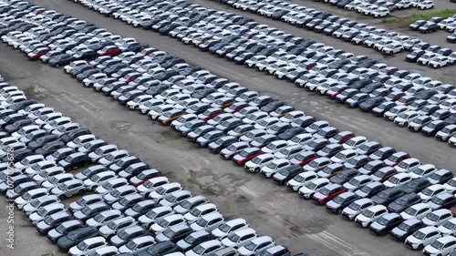 Aerial view of a massive car storage facility showcasing organized rows of new automobiles awaiting international shipment and distribution aerial drone shot
