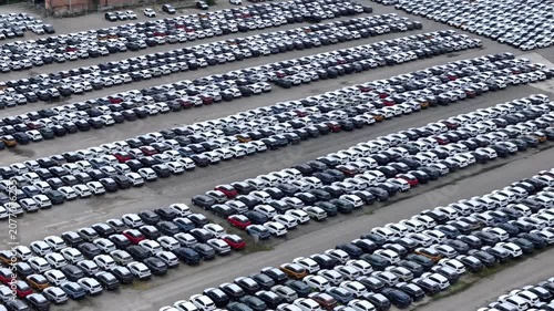 Aerial view of a vast car storage yard filled with numerous vehicles awaiting shipment and distribution globally aerial drone shot