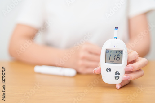 Photos Hand checking Diabetes or Blood glucose self testing by digital blood glucose meter with lancet pen
