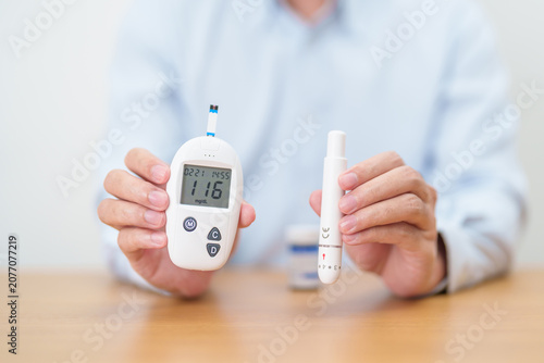 Obraz na płótnie Hand checking Diabetes or Blood glucose self testing by digital blood glucose meter with lancet pen