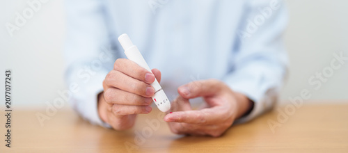 Bilde på lerret Hand using lancet pen on finger with Blood drop glucose testing or Diabetes checking by digital blood glucose meter