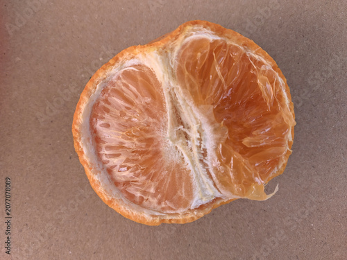 Top view of a peeled halved mandarin orange showing fresh juicy tecture on a brown background.