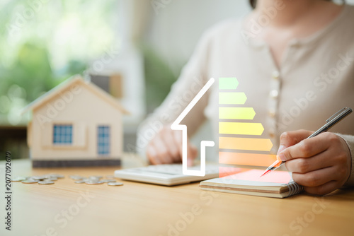 Obraz na plátně Home energy efficiency calculation with house model, calculator and energy rating scale, illustrating renewable energy planning, cost savings, ROI analysis, and sustainable property investment