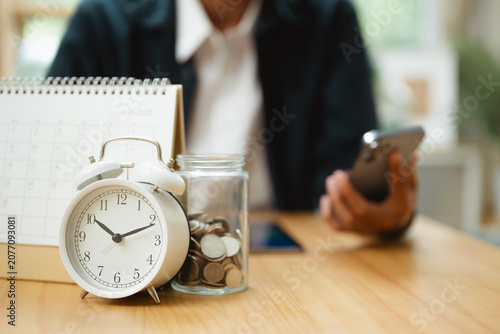 Valokuva Alarm clock, calendar, and savings jar represent bill payment reminders, budgeting, and financial organization