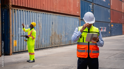 Photos Port worker using a radio transceiver to control a crane loading container boxes