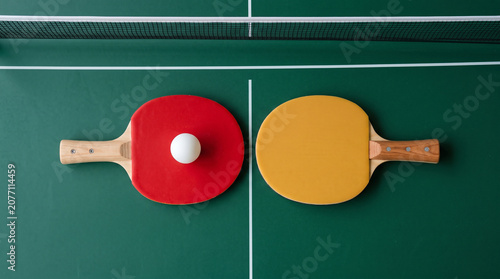 Cuadro en lienzo Top view of two ping pong rackets, one red and one yellow, with a white ball on
