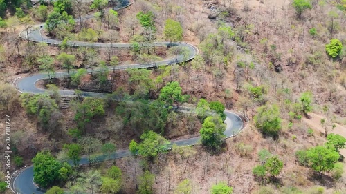 Beautiful aerial view of Wilson Hills located in Gujarat- India, A high-resolution aerial drone photograph of a winding mountain road featuring multiple hairpin bends through a dry deciduous forest