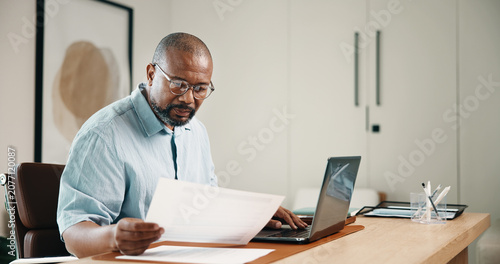 Laptop, finance and black man with documents in home for budget planning, audit or expenses. Mature person, accounting or paperwork with computer for financial assessment, review or report in house