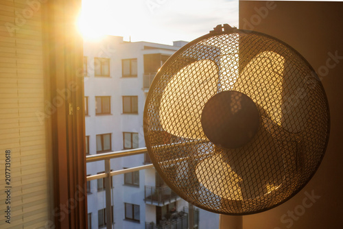 Foto Electric fan ventilating a room on a hot summer morning.