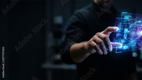 Close up of a man interacting with a glowing blue holographic data interface in a dark room. Perfect for futuristic technology, artificial intelligence, and advanced data analysis concepts.