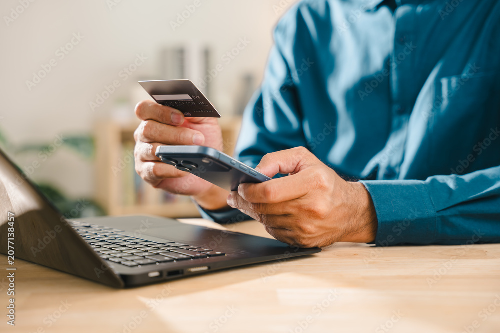 Fototapeta premium Smartphone, digital, display, cyber, security, online, shopping, protection concepts help man holding credit card use laptop for secure internet and networking payment transactions