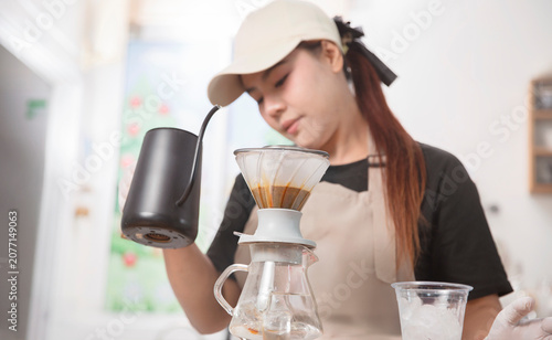Slika na platnu Young Asian barista carefully prepares handcrafted pour-over coffee using a gooseneck kettle in a modern coffee shop, emphasizing specialty coffee craftsmanship