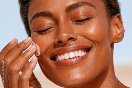 Smiling woman applying moisturizer in close-up beauty skincare portrait with healthy glowing skin