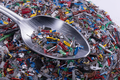 A spoonful of multicoloured plastic components on a background of waste.