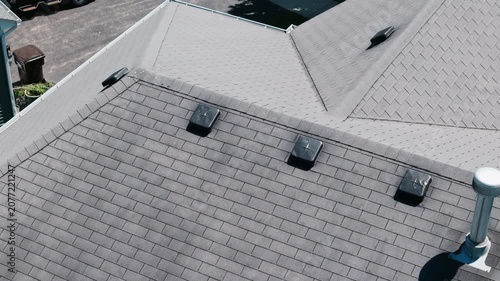 Aerial Drone shoot of a residential house roof with asphalt shingles, roof vents, and modern roofing construction in a suburban neighborhood.
