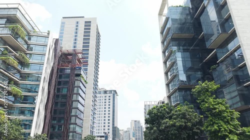 Skyscrapers Cityscape with Modern Highrise Facades, Blue Glass Windows and Greenery Trees in Sunny Daylight