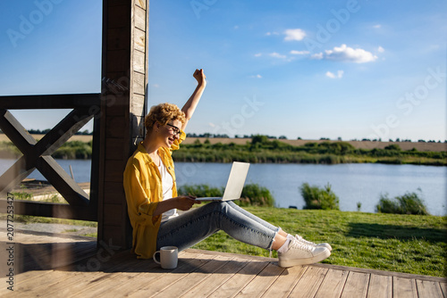 Photos A happy woman with short blonde hair and glasses raises her fist in triumph whil