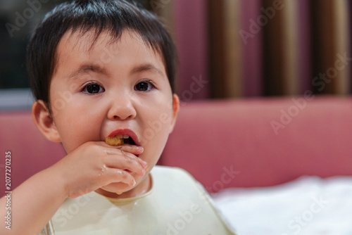 Obraz na płótnie Close-up portrait of a cute little girl eating with her hands at home