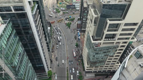 City Street Aerial View Between Modern High Rise Buildings with Traffic Flow and Pedestrians Along the Avenue
