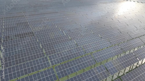 Solar Panel Array with Grid Lines and Reflective Surfaces Along an Industrial Energy Facility Rooftop