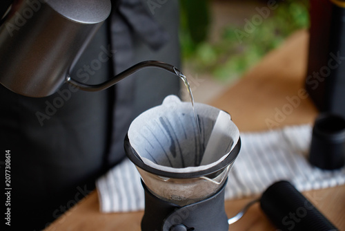 Fotografija Person making drip coffee at home pours hot water from a gooseneck kettle into a paper filter