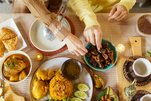 Overhead view of hands reaching for dates at iftar table