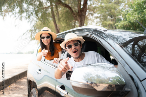 A happy couple enjoying a sunny road trip to the beach, smiling out the car window and embracing the freedom of travel together.