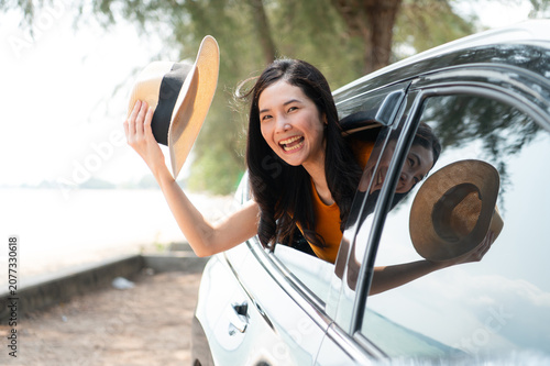 A joyful traveler is feeling the coastal breeze as she drives her SUV. Dressed in a chic sun hat and sunglasses and the calm ocean backdrop completing this perfect getaway