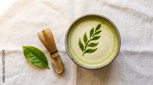 Matcha latte art bowl bamboo whisk green leaf white linen overhead, food lifestyle flat lay