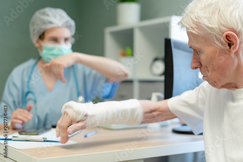 Fotografia Senior man reaching out to doctor during medical consultation