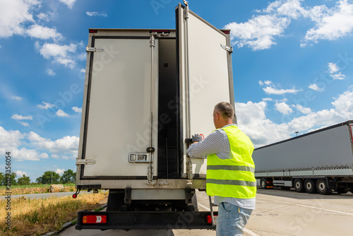 Foto Driver standing near open cargo doors of reefer truck