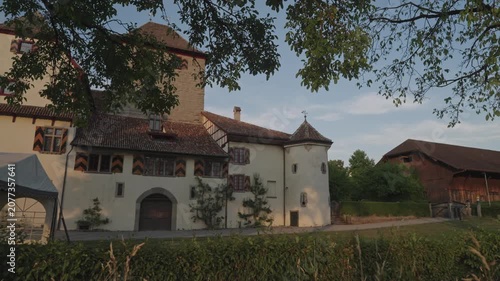 Pan shot of Hegi castle at Swiss city of Winterthur on a sunny summer sunset with branches and meadow in the foreground. Video shot June 27th, 2026, Zurich Winterthur Hegi, Switzerland.
