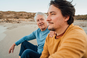 Father and son having discussion on beach at sunset