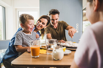 Mother looking at son while father cutting pie at home