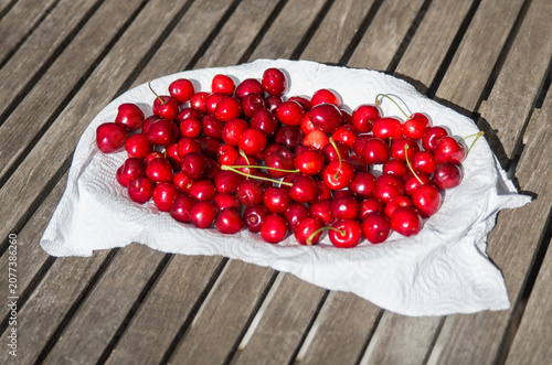 Foto Many tasty fresh sweet cherries lying flat on oval plate with white paper towel,