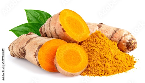 Fresh whole and sliced turmeric roots with a pile of turmeric powder and green leaves, isolated on white background