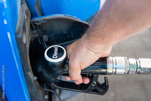 фотографія Man hand using gasoline nozzle to refuel vehicle