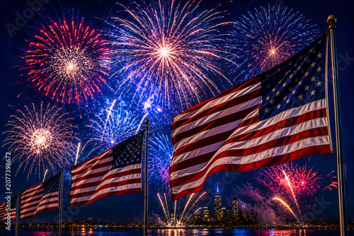 Fireworks in vibrant patterns with waving American flags across a blue celebration sky
