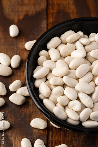 Uncooked white beans on a wooden background