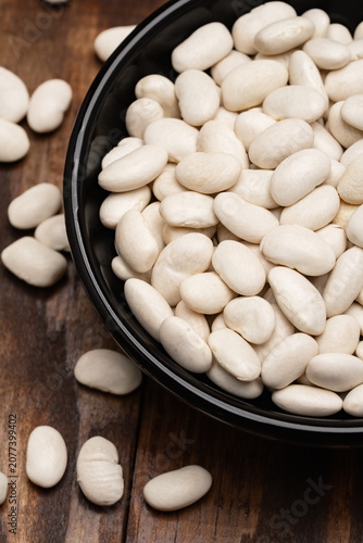 Uncooked white beans on a wooden background