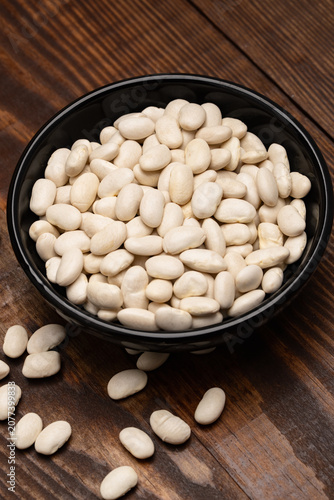Uncooked white beans on a wooden background
