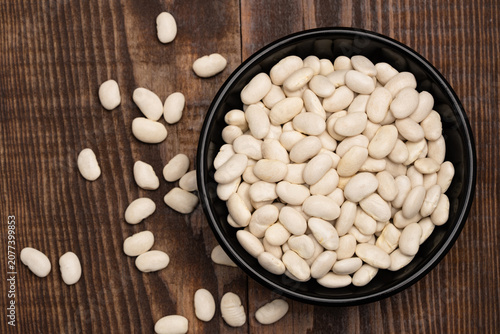 Uncooked white beans on a wooden background