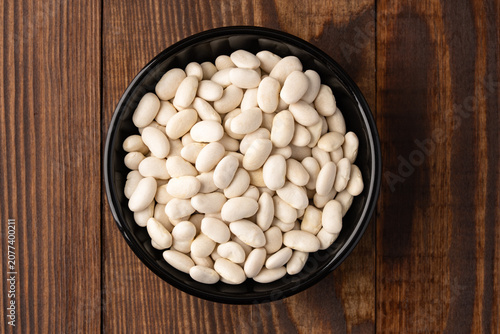Uncooked white beans on a wooden background
