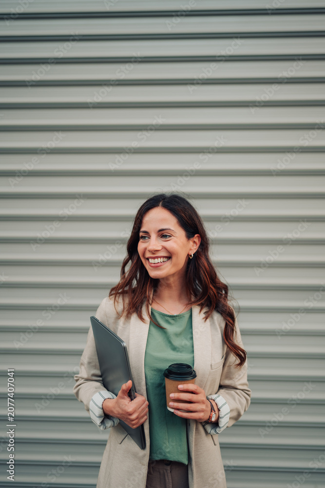 Fototapeta premium Happy woman holding laptop and coffee, smiling for career success and business professionalism