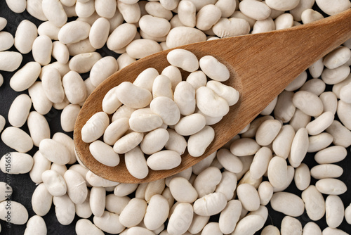 Uncooked white beans on a wooden background