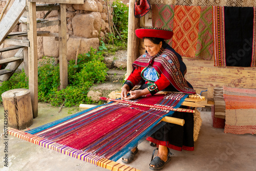 Andean woman weaving colorful textile on traditional loom in Peruvian village